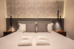 Enjoy restful nights in this beautifully designed bedroom with a plush king-size bed dressed in stylish gray and white linens. Soft lighting accentuates the textured wall, and sleek nightstands bring a modern touch to your stay.