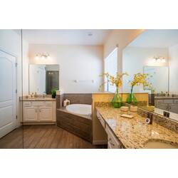 Relax in a spacious bathroom with a luxurious soaking tub and elegant granite countertop. Natural light highlights beautiful floral arrangements and thoughtful design, creating a refreshing and inviting atmosphere for your stay.