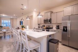 Experience a stunning kitchen with sleek stainless steel appliances and a spacious island perfect for gatherings. The warm pendant lights enhance the chic cabinetry, setting a delightful atmosphere for cooking and socializing.