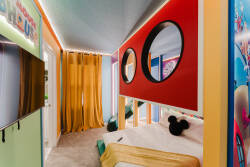 Experience a vibrant sanctuary filled with playful colors and creative decor that enhance your stay. A bold red accent wall and circular mirrors create a whimsical atmosphere, while soft textiles provide comfort and warmth.