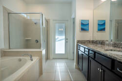 Enjoy a bright, airy bathroom featuring a spacious glass-enclosed shower and a luxurious soaking tub. The sleek dark cabinetry and granite countertops create a stylish look, while natural light enhances the refreshing atmosphere.