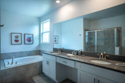 Relax in a beautifully designed bathroom with a spacious double vanity, elegant gold fixtures, and a luxurious soaking tub—ideal for unwinding after your adventures. Natural light fills the space, adding to its charm.