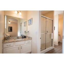 Step into a bright bathroom featuring a spacious double vanity with elegant granite countertops and ample storage. The glass shower enclosure complements the neutral tones, creating a clean and refreshing atmosphere for your stay.