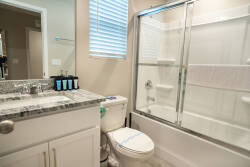 Enjoy a refreshing bathroom with a sleek granite countertop and glass-enclosed shower. Natural light brightens the clean, modern design, while thoughtful amenities are conveniently arranged for your comfort.