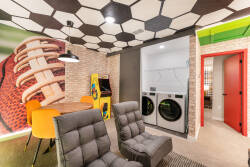 Enjoy a vibrant game room featuring a unique hexagonal ceiling and lively sports decor. Unwind in cozy gray recliners or cheerful orange dining chairs, perfect for gatherings, while a handy laundry area makes your stay effortless.
