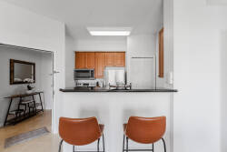 Step into your culinary haven, where rich wooden cabinets contrast beautifully with sleek black countertops. Enjoy casual meals at the stylish brown leather bar stools, all bathed in natural light from the skylight above.