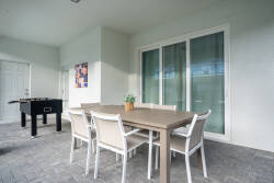 Step outside to a spacious patio with a sleek dining table and comfortable chairs, ideal for alfresco meals. The neutral tones and large sliding glass doors let in natural light, creating a relaxed atmosphere for your enjoyment.