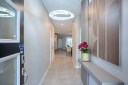 Step into a beautifully designed hallway with light tiles and a striking modern chandelier. The elegant decor, with soft hues and a vibrant floral arrangement, welcomes you into a warm and inviting atmosphere for your stay.