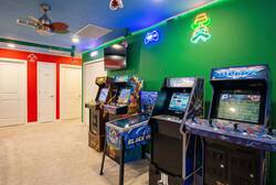 Enjoy a fun game room corner with arcade machines, colorful controls, a wall-mounted TV, bright green walls, and playful decor, creating a great space for family entertainment during vacation.