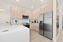 Welcome to a bright kitchen featuring light wood cabinetry and sleek stainless steel appliances that blend style and functionality. The spacious island is ideal for casual dining, creating a clean and inviting atmosphere.