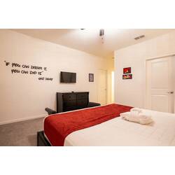 Relax in a stylish Mickey-themed bedroom with a bold character mural, elegant tufted headboard, soft carpet, and playful red, black, and white accents. Bright windows, cozy lighting, and fun Disney-inspired details create a cheerful and comfortable r