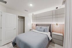 Experience tranquility in this beautifully designed bedroom with a cozy blue duvet and stylish bedside tables featuring built-in lighting.