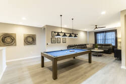 Enjoy a stylish game room with a vibrant blue pool table perfect for friendly competition. Modern furnishings and warm wood tones provide a cozy atmosphere, while large windows fill the space with inviting natural light.