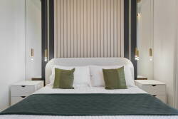 This serene bedroom boasts a plush headboard with elegant slats and soft tones for relaxation. The lush green throw and decorative pillows add comfort, while sleek bedside tables elevate the modern aesthetic.