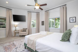 Enjoy a beautifully styled bedroom filled with natural light, featuring a plush king-sized bed with crisp linens. Large windows provide serene views, while a cozy armchair and soft lighting create an ideal relaxation spot.