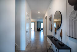 Welcome to a bright entryway featuring a stylish console table and contemporary art, creating an inviting atmosphere. The sleek tile floor leads you to a spacious living area bathed in natural light, enhancing the modern decor.
