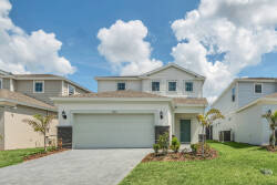 This charming vacation home features a welcoming façade with clean lines and elegant stone accents, all framed by vibrant green landscaping. The spacious driveway leads to an inviting entryway, perfect for a warm arrival.