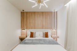 Experience restful nights in this beautifully designed bedroom, featuring a sleek wooden accent wall and soft lighting that creates a cozy ambiance. The plush bedding and stylish throw pillows add a touch of comfort to your stay.