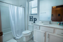 Bright and functional, this bathroom features a clean white color palette complemented by sleek cabinetry and a large mirror that enhances the space. Enjoy the convenience of a traditional layout with ample room to move freely.