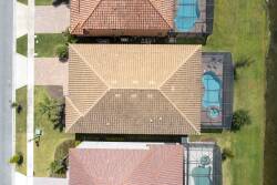 Experience the charm of this beautifully designed home with its terracotta roof and inviting outdoor spaces. The lush green yard and the shimmering pools create a perfect backdrop for relaxation and leisure under the sun.