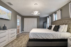Experience the cozy ambiance of this thoughtfully designed bedroom, featuring soft gray walls, plush carpeting, and a charming chandelier. Relax in the elegant bedding and decorative pillows after your day of adventure.