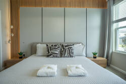 Experience a beautifully designed bedroom with a plush king-sized bed and stylish accent pillows. The warm wood paneling and soft natural light create a cozy atmosphere for restful nights and refreshing mornings.