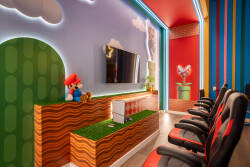 Step into a vibrant gaming room where whimsical decor meets comfort, featuring bold red and blue stripes and plush gaming chairs. The playful wall art and cozy seating create an engaging atmosphere for entertainment and fun.