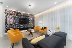 Brighten your stay in this stylish living room, featuring bold orange armchairs that pop against a striking black-and-white accent wall. Natural light dances through sheer curtains, creating a warm atmosphere perfect for relaxing.