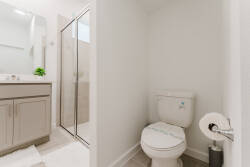 Experience a beautifully designed bathroom with soft gray cabinetry and a sleek glass-enclosed shower. The bright lighting adds to the fresh, clean aesthetic, making it a welcoming and functional space for your stay.