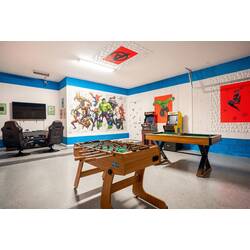 Enjoy a bold superhero-themed game room with foosball, pool table, arcade games, gaming chairs, and a wall-mounted TV. Colorful murals and bright blue accents create a fun space for kids, teens, and adults to play together.