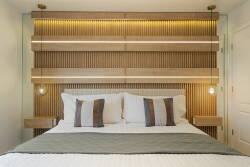 This stylish bedroom boasts a stunning wooden accent wall with soft lighting that creates a warm glow. The plush bedding and decorative pillows invite relaxation, while sleek nightstands add a modern touch for a cozy retreat.