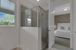 Freshen up in a bright en-suite bathroom with a glass walk-in shower, tiled walls, natural light, and direct access to a cozy bedroom, offering comfort and privacy.