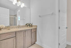 Freshen up in a bright bathroom with a granite vanity, large mirror, modern lighting, soft neutral tones, floral decor, and a clean layout for a comfortable stay.