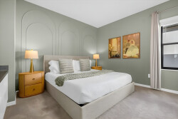 Welcome to a serene bedroom with soft green walls, inviting plush carpet, and warm bedside lighting, creating the perfect ambiance for relaxation. The tasteful artwork adds a charming touch to your restful retreat.