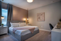 Unwind in this beautifully designed bedroom, featuring a plush king-sized bed with soft linens and stylish pillows. The warm tones and pendant lights create a cozy ambiance, perfect for relaxing after your adventures.