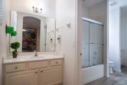 Experience a bright bathroom with a spacious vanity and a large mirror that enhances natural light. Enjoy modern comfort in the sleek glass shower, all beautifully accented by neutral tones and subtle decor.