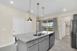 This bright kitchen boasts sleek gray cabinetry and a beautiful granite island, ideal for casual meals or entertaining. Oversized windows fill the space with natural light, creating a warm and inviting atmosphere for you to enjoy.