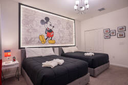 This bright and playful bedroom offers two plush beds with soft linens, perfect for unwinding after your adventures. A whimsical Mickey Mouse mural and stylish fixtures create a cheerful and inviting atmosphere for your stay.