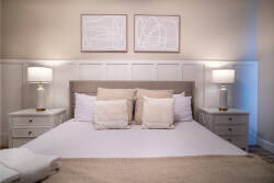 This cozy bedroom welcomes natural light, showcasing plush bedding and soft neutral tones. Two bedside lamps create a warm glow, while modern art above the bed adds style, perfect for unwinding after your adventures.