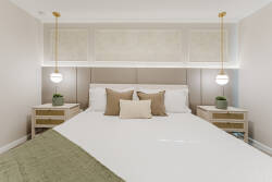 This sophisticated bedroom blends tranquility and style, featuring a plush, neutral-toned bed adorned with decorative pillows. Warm pendant lights illuminate the space, while the elegant nightstands add a touch of modern charm.