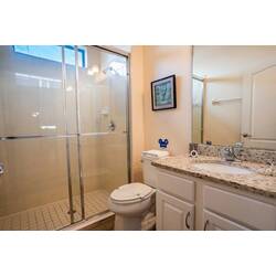 Experience a bright bathroom with sleek glass shower doors and a luxurious granite countertop. Natural light enhances the thoughtful decor and modern fixtures, creating a space designed for your comfort and convenience.
