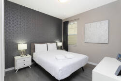 This cozy bedroom boasts a stylish accent wall and soft lighting from sleek bedside lamps. With plush white bedding and modern furniture, it's the ideal space to relax after a day of exploration.