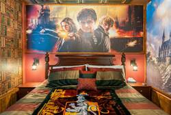 Rest in a magical wizard themed bedroom with a cozy four poster bed, library wall design, warm lighting, rich colors, and detailed ceiling decor, creating a fun and immersive space for vacation.