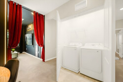 Discover a stylish laundry nook with sleek white appliances against soft beige walls. Elegant red curtains add warmth, inviting you to enjoy the nearby space designed for relaxation and convenience.