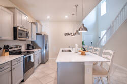 Experience a relaxing vacation in this stylish kitchen featuring stainless steel appliances and soft gray cabinetry. The spacious island with seating is ideal for casual dining and socializing, all under beautiful natural light.
