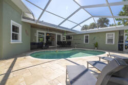Welcome to your sunlit oasis with a refreshing pool in a spacious screened enclosure, perfect for relaxing afternoons. The sleek stone patio and inviting seating area are ideal for casual gatherings with friends.
