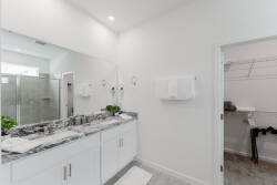 This bright bathroom features a spacious double vanity with sleek granite countertops and plenty of storage. Natural light highlights the modern glass shower, creating a refreshing atmosphere perfect for your relaxation.