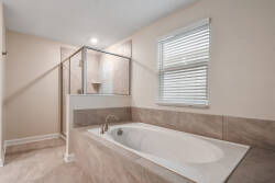 Experience a bright and spacious bathroom with elegant tan tile and a luxurious soaking tub, ideal for relaxing after your adventures. Natural light fills the space, enhancing the fresh feel of the modern design.