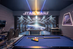 Discover a vibrant game room featuring a stylish pool table, colorful lighting, and a striking Star Wars mural. Enjoy comfortable seating in a fun atmosphere ideal for playful competition and relaxation.