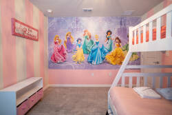 Enhance your stay in this delightful kids' room with a charming princess mural that sparks imagination. The soft pink and white stripes create a playful ambiance, paired with cozy bunk beds for a restful night.